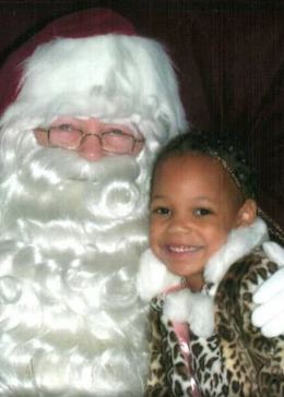 A young May wearing a leopard print coat while sitting next to the one and only Santa Claus