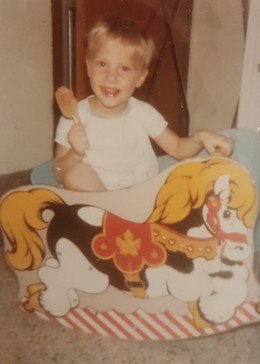 A young Michel riding a wooden horse